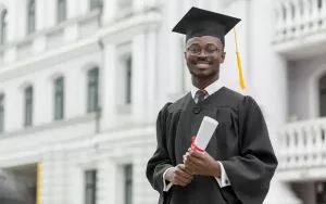 Estudante em sua formatura, vestindo uma beca e segurando seu diploma, que pode ser conferido para a licenciatura, bacharelado e tecnólogo.