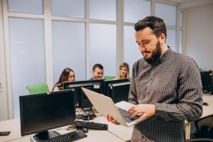 Homem atua no mercado de gestão da tecnologia da informação ao comandar o time de TI de um negócio. Quatro pessoas trabalham.