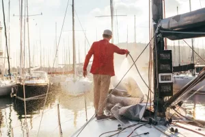 A imagem mostra um homem em um porto lavando seu barco. É possível ver vários barcos em volta, além de um equipamento para a pesca.
