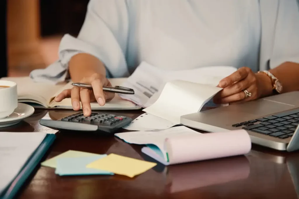 Mulher faz os cálculos com juros compostos para determinar como economizar melhor o seu dinheiro. Ela usa uma calculadora.